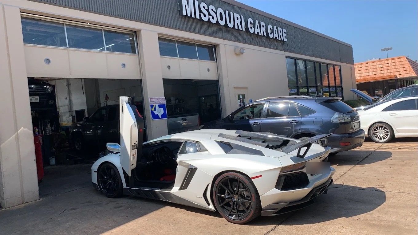 White Lamborghini Aventador with scissor doors open in front of Missouri Car Care